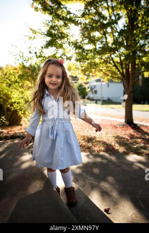 Beautiful little girl blond curls pink bow smiling outdoors Stock Photo