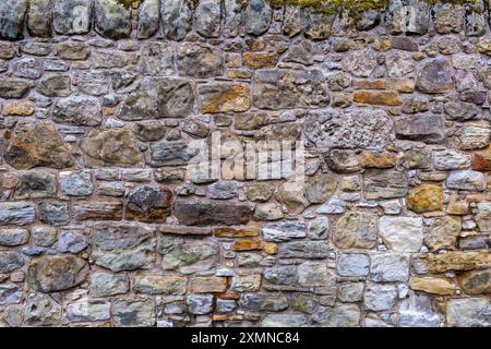 Detail of a traditional dry stone masonry wall recently renovated with sand textured concrete cement. Stock Photo