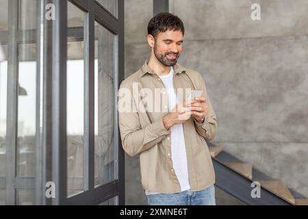 Smiling Man Using Smartphone Near Modern Building Stock Photo