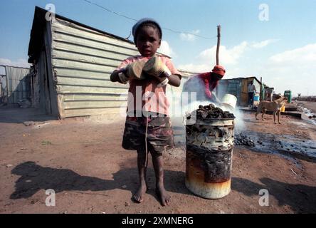 Barefoot Township kid in Soweto, South Africa uses shoes to keep his hands warm1996  Picture by Roger Bamber Stock Photo