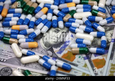 Pills in capsules scattered on US dollars currency. Concept of health care in USA, pharmaceutical business, drug prices, pharmacy, medicine Stock Photo