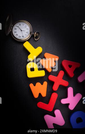 Pocket watch and colorful Letters of Alphabet made of wood Stock Photo