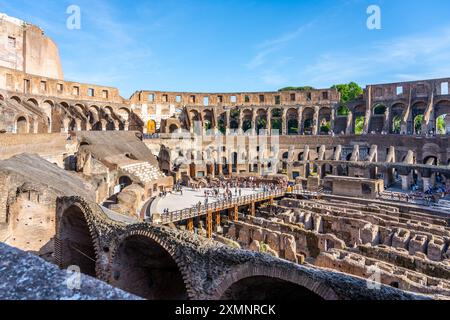 A scenic view of the Colosseum in Rome, Italy, during sunset. The ancient amphitheater is bathed in golden light, with crowds of people enjoying the warm evening. Stock Photo