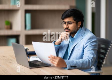 Businessman Reading Documents at Desk in Office Stock Photo