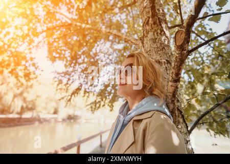 Woman in Sunglasses Leaning Against a Tree Stock Photo