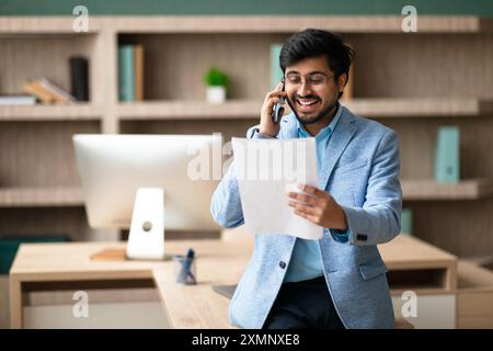 Businessman Discussing Documents on Phone in Office Stock Photo