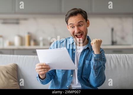 Excited Man Reading Good News on Paper at Home Stock Photo