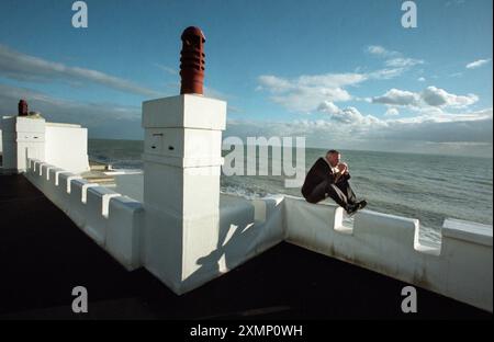 Picture by Roger Bamber : 12 February 1999: Portrait of Music DJ and ex Housemartin Norman Cook, aka Fatboy Slim on the balustrade roof terrace of his Brighton and Hove seafront home; sitting; dreaming; dreamy; contemplative; thinking; musing; celebrity; showbiz star; singer; DJ; at home; seaside; beach; ocean; sussex; england; uk; great britain; outside; alone; worried; anxious; Stock Photo