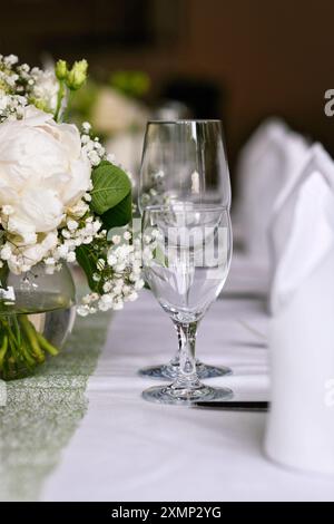 Wedding table setting with elegant water and wine drinking glasses and white flowers Stock Photo