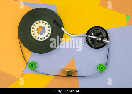 Top view of turntable arm on old vintage retro audio tape cassettes with a background of multicolored paper sticky notes Stock Photo