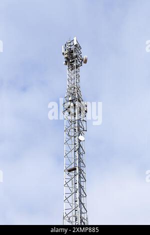 A tall telecommunication tower antenna in a sky with clouds. Stock Photo