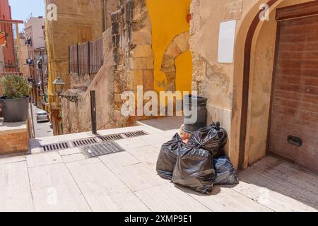 Neatly stacked waste bags await pickup at a street corner in Tarragona. Stock Photo