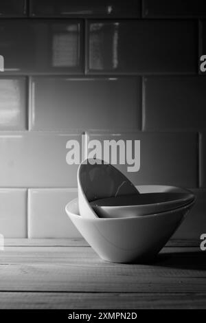 Stacked ceramic bowls on wooden surface in black and white Stock Photo