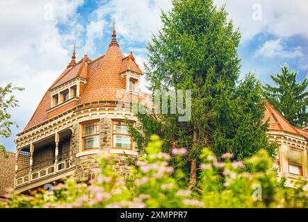 Germantown, Philadelphia, USA, July 29, 2024. Charming manor house with red terracotta roof, wooden carvings surrounded by flowers and greenery Stock Photo