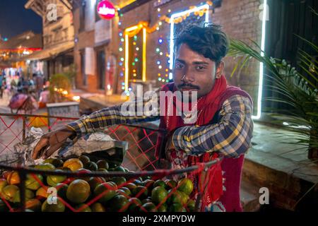 Street vendor with basket of fruit for sale at night during  November Diwali festival of lights, Kathmandu, Nepal Stock Photo