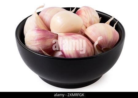 Fresh unpeeled garlic cloves in black ceramic bowl isolated on white. Stock Photo