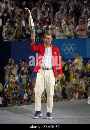 Paris, Ile de France, France. 26th July, 2024. Spanish tennis star RAFAEL NADAL carries the torch in the rain at the Paris 2024 Olympics opening ceremony. (Credit Image: © Mark Edward Harris/ZUMA Press Wire) EDITORIAL USAGE ONLY! Not for Commercial USAGE! Stock Photo