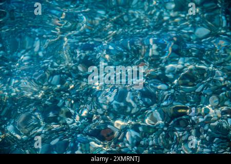 multi-colored stones under water on the sea, river. Natural background of stones, glare on the water Stock Photo