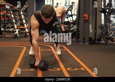 Athletic man doing dumbbell plank row in fitness gym. Fitness gym training. Fitness strength workout Stock Photo