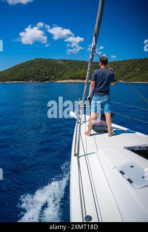 Young man captain on the yacht looking through binoculars during sailing boat. Travel and active life. Yachting Stock Photo