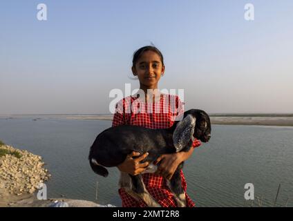 Portrait of smiling girl carrying a baby sheep, Rajshahi Division, Rajshahi, Bangladesh Stock Photo