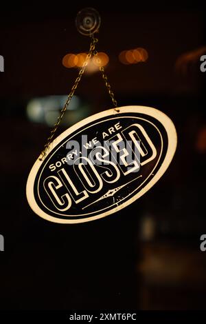 'Sorry, we are closed' sign on shop door at night Stock Photo