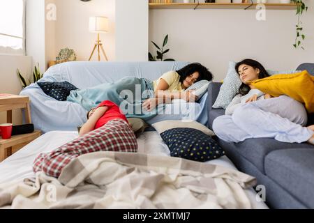 Three young female friends sleeping on the sofa after slumber party Stock Photo