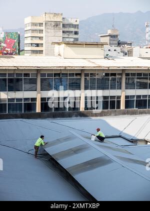 Two workers repairing a roof before the rainy season in San José, Costa Rica. Stock Photo