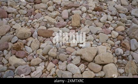 Various colored rocks and stones scattered on a ground in an outdoor setting, showcasing nature's diversity in shapes and textures Stock Photo
