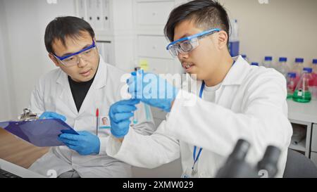 Two male scientists are working together in a laboratory with one holding a test tube and the other checking a report. Stock Photo