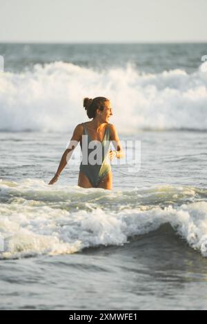 Attractive woman smiling as she walks along the shore with water on her thighs Stock Photo