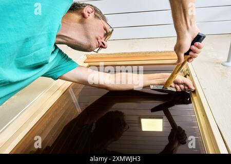 Homeowner DIY nailed door jamb to sauna door opening with hammer. Stock Photo