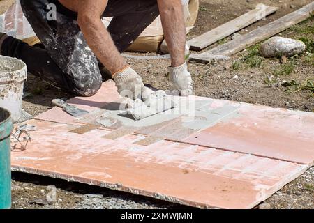Applying cement-based adhesive mortar to thin flexible panel of fake brickwork to finish facade of house. Stock Photo