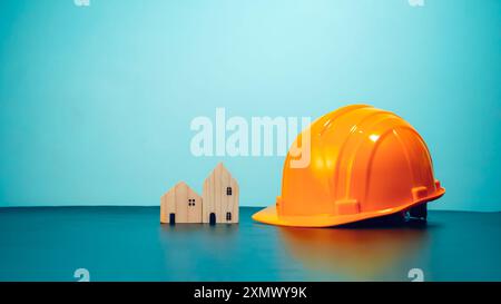 Hard hat for construction site workers and for engineers or workers, Standard safety helmet head protection, Wooden house model with hard hat with cop Stock Photo