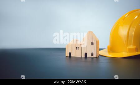 Hard hat for construction site workers and for engineers or workers, Standard safety helmet head protection, Wooden house model with hard hat with cop Stock Photo
