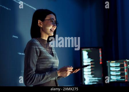 asian woman programmer standing in front of a screen with code projected  presentation the integration of technology and human expertise in software d Stock Photo