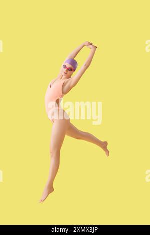 Professional young female swimmer jumping on yellow background Stock Photo