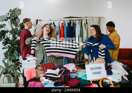young people in second hand shops, choice of clothes, the possibility of a second life for clothes, woman take away each other's clothes, having fun Stock Photo