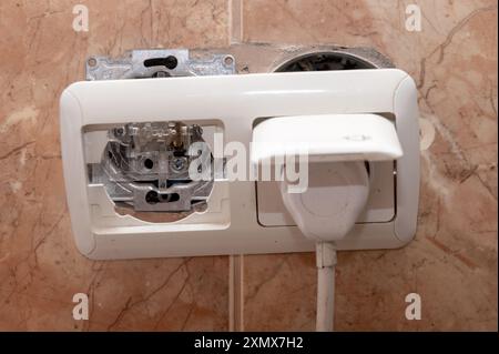 Broken socket on ceramic tile wall.  Broken outlet. Concept of risk of electric shock Stock Photo