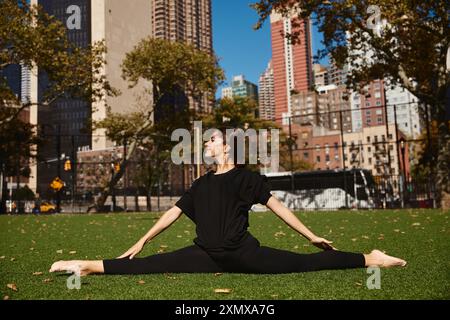 A young woman performs a split on a grassy park in the heart of New York City. Stock Photo