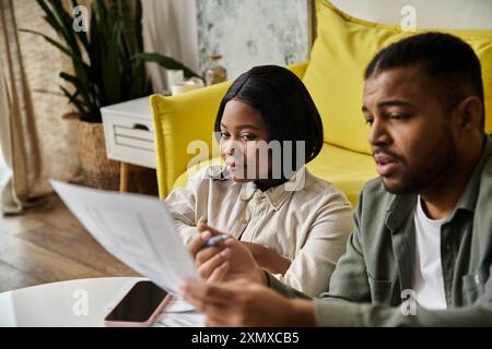 A couple sits together at home, reviewing documents. Stock Photo