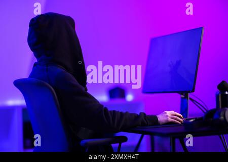 Professional gamer in hoody playing video game in a colorful room with a modern setup Stock Photo