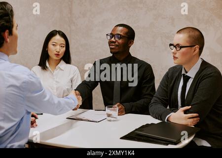 Ethnically diverse HR managers thanking unrecognizable male applicant for interview and doing handshake Stock Photo