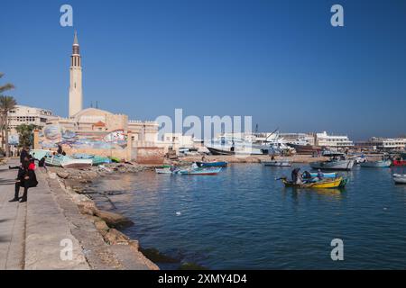 Alexandria, Egypt - December 14, 2018: Coastal view of the old fishing harbor of Alexandria. Fishermen are in wooden boats, ordinary people walk the s Stock Photo