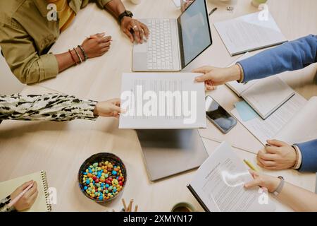 From above view of unrecognizable young business partners working on contract during meeting in office Stock Photo