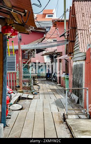 A view down an alleyway with wooden boardwalk flooring on The Chew Jetty in George Town, Penang, Malaysia. Stock Photo