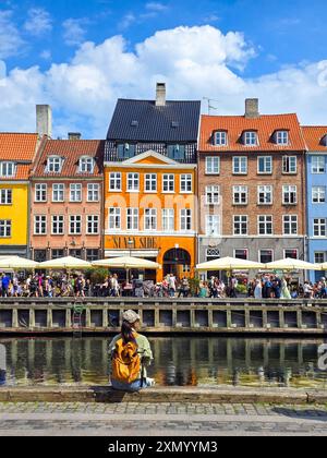 Copenhagen Nyhavn Canal Denmark 21 July 2024, People gather by the vibrant waterfront, enjoying food and conversation while the sun shines on charming Stock Photo