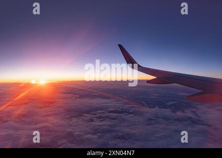 Airplane flying low over snowy mountains and preparing for landing to the airport, view from plane window of wing turbine and skyline Stock Photo