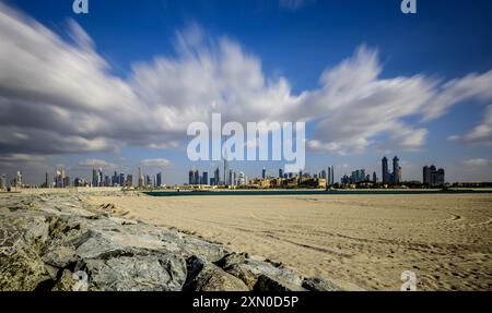 Fast-moving clouds over Dubai skyline on a bright day, showcasing the city's stunning skyscrapers Stock Photo