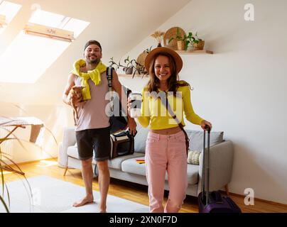 Young couple with their lapdog at home getting ready for summer vacation. Stock Photo